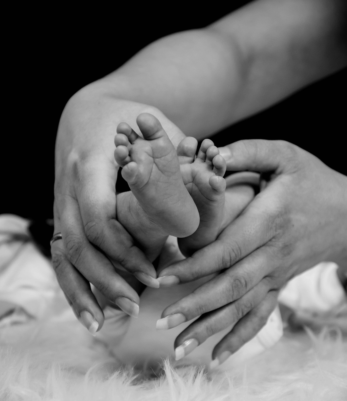 Close-up of a newborn baby’s feet cradled in their parents’ hands