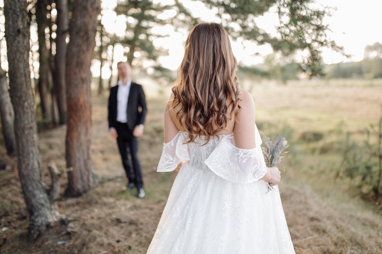 Bride walking through a golden-hour field as the groom approaches